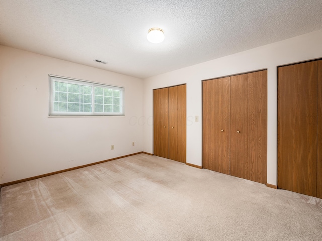 2594 Roberts Ct, Hilliard, OH 43026 - unfurnished bedroom with two closets, carpet floors, baseboards, and a textured ceiling