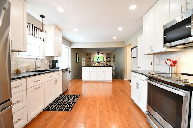 6736 Worthington Galena Rd, Worthington, OH 43085 - kitchen featuring stainless steel appliances, a sink, dark countertops, backsplash, and white cabinetry