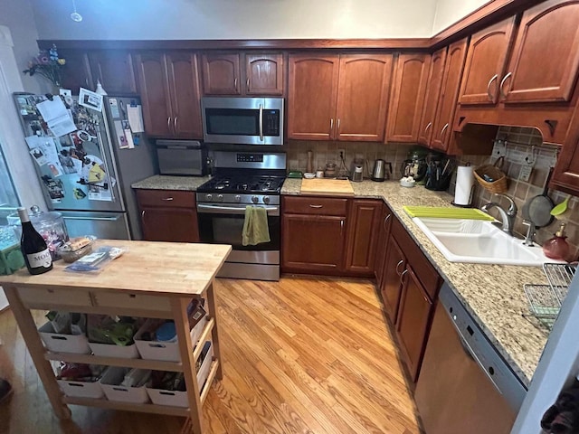 688 S 5th St, Columbus, OH 43206 - kitchen featuring appliances with stainless steel finishes, a sink, light wood-style floors, and tasteful backsplash