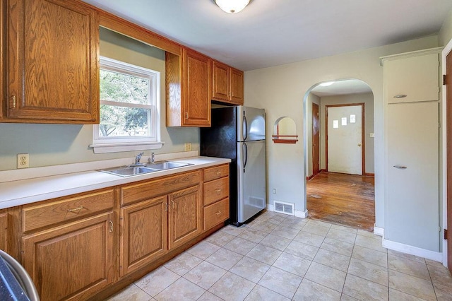 11 Mermary Dr, Fredericktown, OH 43019 - kitchen featuring a sink, arched walkways, freestanding refrigerator, light tile patterned floors, and brown cabinetry