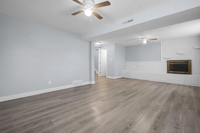 4980 Comstock Dr, Columbus, OH 43232 - unfurnished living room featuring a ceiling fan, a brick fireplace, stairs, wood finished floors, and brick wall