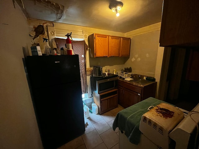 40 Wisconsin Ave, Columbus, OH 43222 - kitchen featuring freestanding refrigerator, stainless steel microwave, light tile patterned floors, and brown cabinets