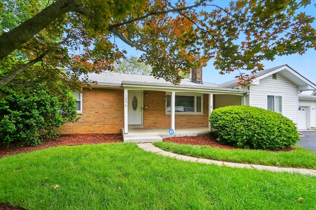 1096 Lancaster Ave, Reynoldsburg, OH 43068 - ranch-style home with a chimney, brick siding, covered porch, a front yard, and a garage