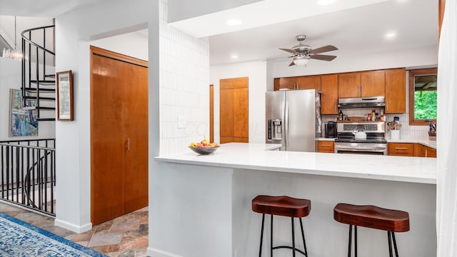 4171 Clotts Rd, Columbus, OH 43230 - kitchen with stainless steel appliances, under cabinet range hood, brown cabinetry, stone finish floors, and ceiling fan