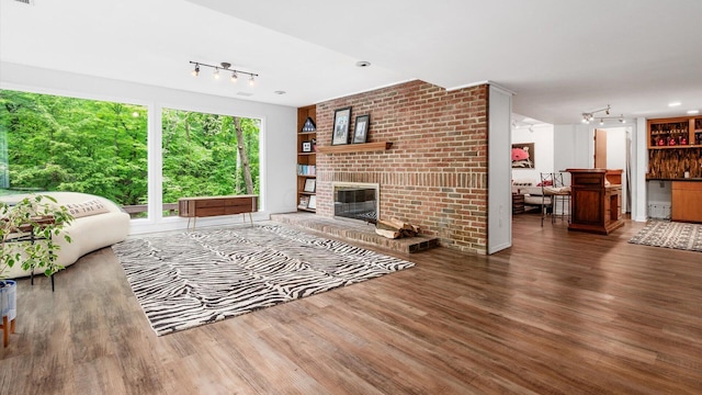 4171 Clotts Rd, Columbus, OH 43230 - living room with track lighting, wood finished floors, a dry bar, and a brick fireplace