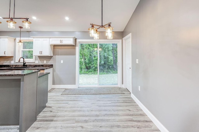 228 E Walnut St, Danville, OH 43014 - kitchen featuring a sink, white cabinetry, light wood-style floors, dark stone countertops, and baseboards