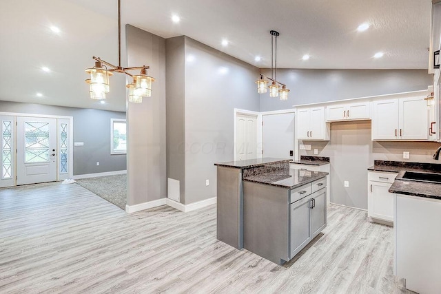 228 E Walnut St, Danville, OH 43014 - kitchen with a sink, a kitchen island, decorative light fixtures, white cabinets, and light wood-type flooring