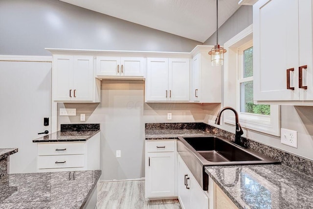 228 E Walnut St, Danville, OH 43014 - kitchen featuring a sink, lofted ceiling, dark stone counters, white cabinets, and decorative light fixtures