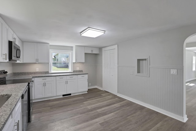 901 E Vine St, Mount Vernon, OH 43050 - kitchen featuring stainless steel microwave, range with electric cooktop, wood finished floors, arched walkways, and light stone countertops