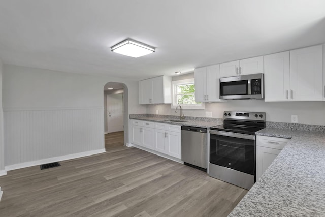 901 E Vine St, Mount Vernon, OH 43050 - kitchen with stainless steel appliances, a sink, arched walkways, light wood-style floors, and white cabinets
