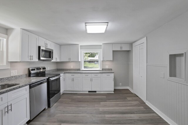 901 E Vine St, Mount Vernon, OH 43050 - kitchen with stainless steel appliances, white cabinets, wood finished floors, light stone counters, and a wainscoted wall