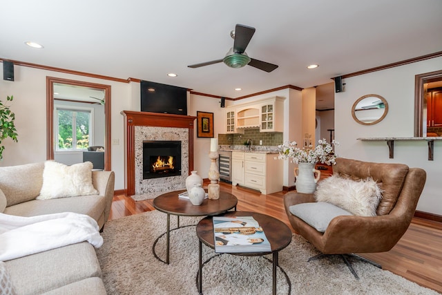 2738 E Broad St, Columbus, OH 43209 - living room featuring beverage cooler, ornamental molding, a fireplace with flush hearth, ceiling fan, and light wood-type flooring