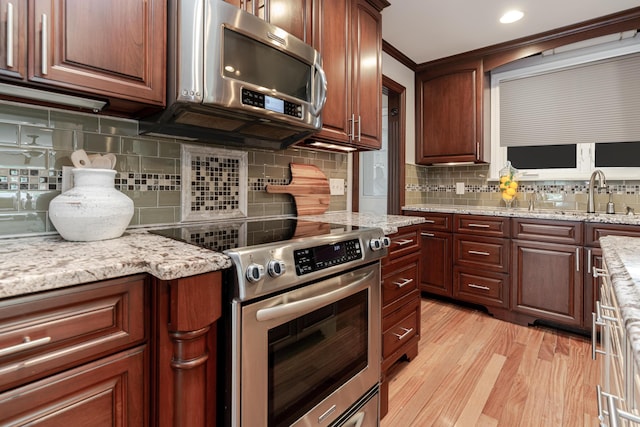 2738 E Broad St, Columbus, OH 43209 - kitchen with stainless steel appliances, light wood-type flooring, tasteful backsplash, light stone counters, and ornamental molding