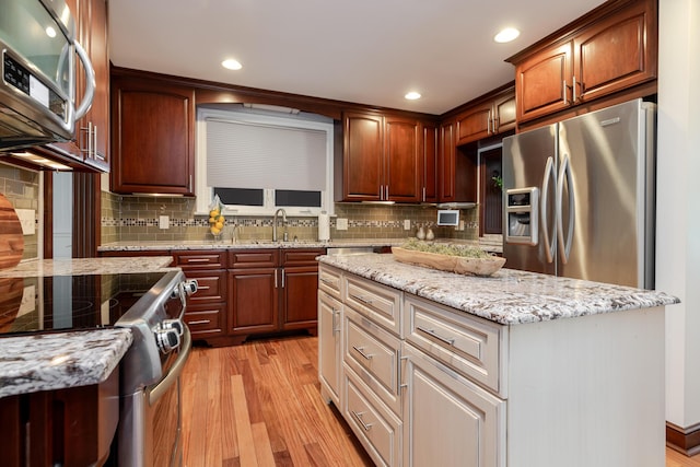 2738 E Broad St, Columbus, OH 43209 - kitchen with stainless steel appliances, light wood-style flooring, light stone counters, decorative backsplash, and recessed lighting