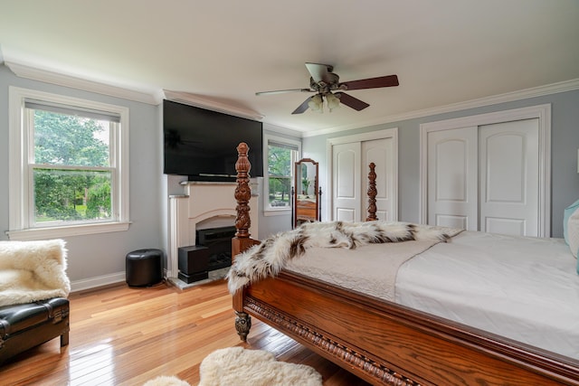 2738 E Broad St, Columbus, OH 43209 - bedroom featuring two closets, ornamental molding, light wood finished floors, a fireplace, and ceiling fan