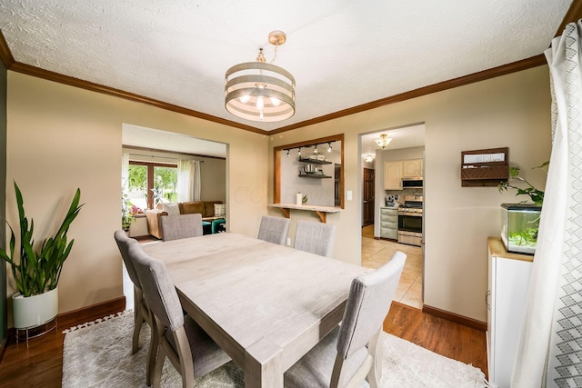2862 Shady Ridge Dr, Columbus, OH 43231 - dining area featuring wood finished floors, crown molding, a chandelier, baseboards, and a textured ceiling