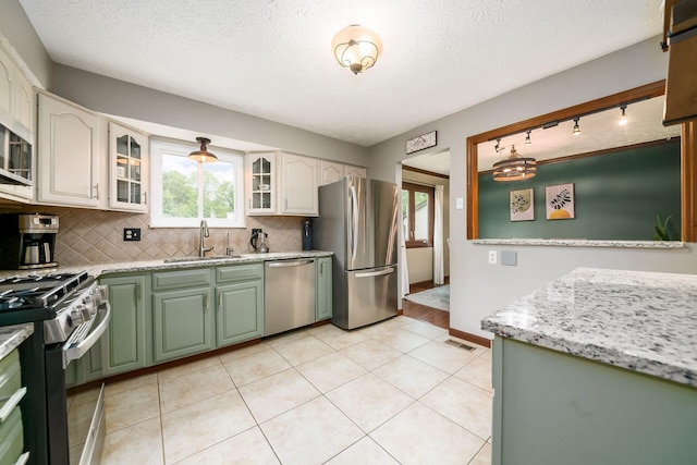 2862 Shady Ridge Dr, Columbus, OH 43231 - kitchen with appliances with stainless steel finishes, a sink, green cabinetry, tasteful backsplash, and a textured ceiling
