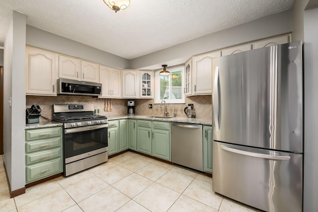 2862 Shady Ridge Dr, Columbus, OH 43231 - kitchen featuring appliances with stainless steel finishes, green cabinetry, a sink, tasteful backsplash, and a textured ceiling