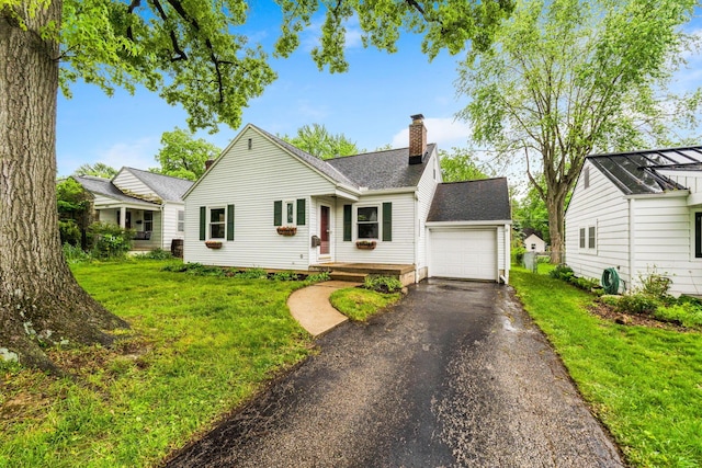 157 E Dominion Blvd, Columbus, OH 43214 - view of front of home with a chimney, driveway, roof with shingles, a front lawn, and a garage