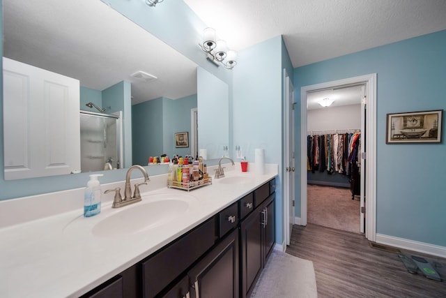2991 Green Line Way, Columbus, OH 43231 - bathroom with a stall shower, double vanity, wood finished floors, a walk in closet, and baseboards