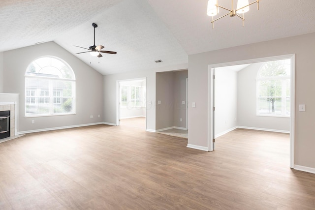 6174 Brickside Dr, New Albany, OH 43054 - unfurnished living room with a ceiling fan, light wood finished floors, lofted ceiling, a chandelier, and a tiled fireplace