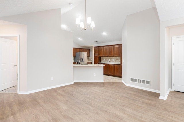 6174 Brickside Dr, New Albany, OH 43054 - unfurnished living room featuring vaulted ceiling, light wood-style flooring, a chandelier, and baseboards