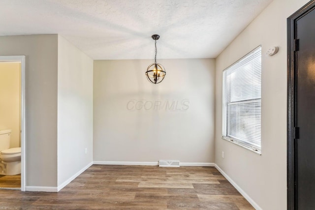 2363 Hampstead Dr Unit 2363-65-67, Columbus, OH 43229 - unfurnished dining area featuring wood finished floors, plenty of natural light, a chandelier, and baseboards
