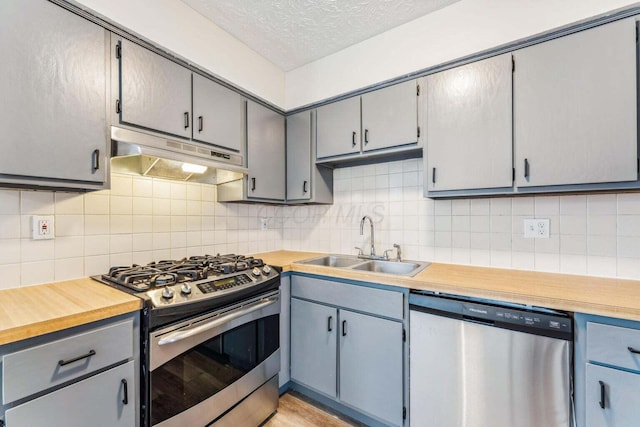2363 Hampstead Dr Unit 2363-65-67, Columbus, OH 43229 - kitchen featuring appliances with stainless steel finishes, under cabinet range hood, a sink, light countertops, and tasteful backsplash
