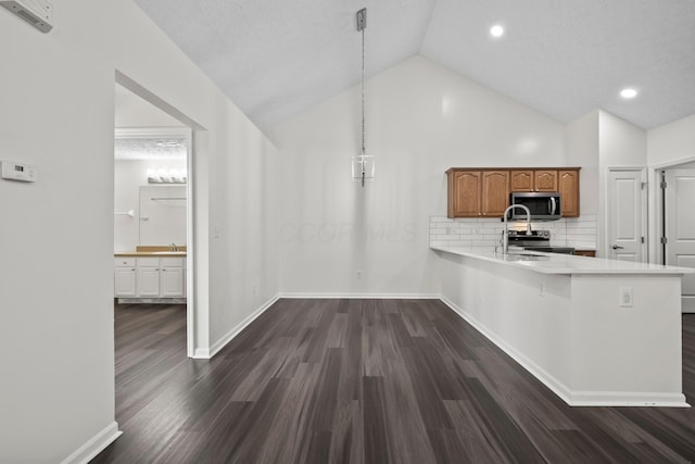 143 Falls Peak Ln, Delaware, OH 43015 - kitchen featuring stainless steel appliances, light countertops, a peninsula, brown cabinetry, and dark wood finished floors