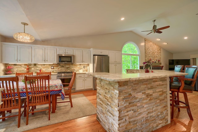 1494 Old Carriage Ct, Canal Winchester, OH 43110 - kitchen with premium appliances, vaulted ceiling, ceiling fan, light wood-style floors, and decorative backsplash