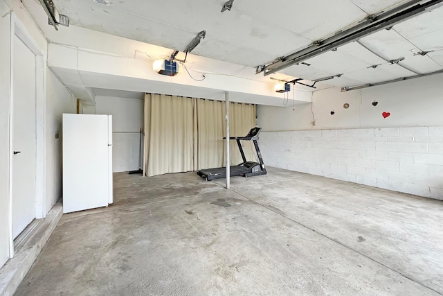6024 Winterberry Dr, Galloway, OH 43119 - garage featuring freestanding refrigerator, a garage door opener, and concrete block wall