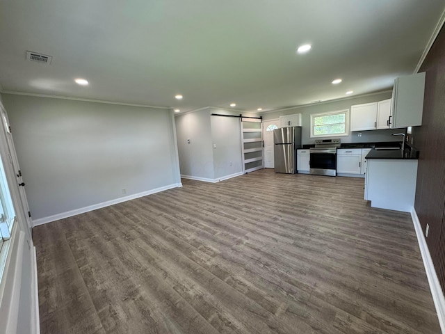 2075 Rankin Ave, Columbus, OH 43219 - unfurnished living room featuring a barn door, crown molding, recessed lighting, dark wood-type flooring, and baseboards
