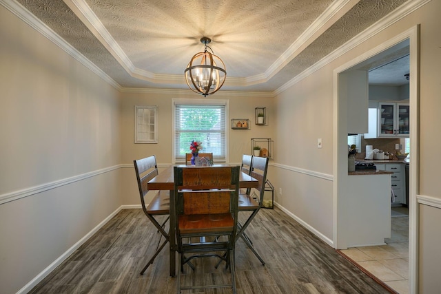 12179 Woodrow Ln, Pickerington, OH 43147 - dining area featuring a chandelier, wood finished floors, a textured ceiling, ornamental molding, and a tray ceiling
