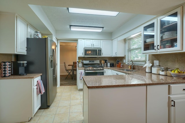 12179 Woodrow Ln, Pickerington, OH 43147 - kitchen featuring appliances with stainless steel finishes, a sink, a peninsula, white cabinetry, and decorative backsplash