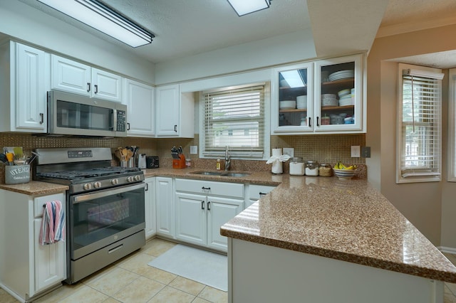 12179 Woodrow Ln, Pickerington, OH 43147 - kitchen with stainless steel appliances, a sink, a peninsula, tasteful backsplash, and white cabinetry