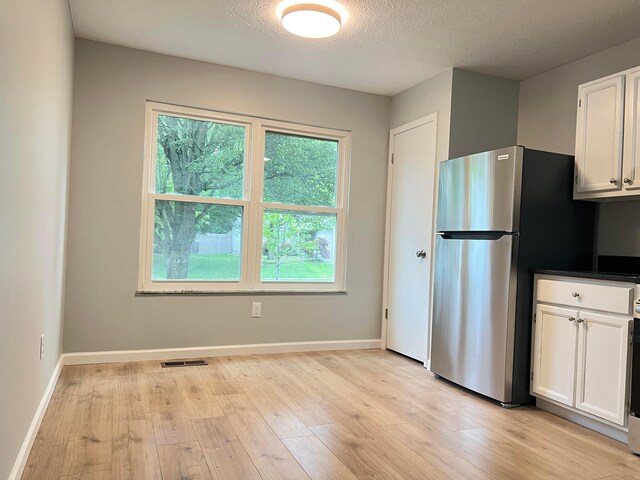 507 Warwick Ln, Pickerington, OH 43147 - kitchen with white cabinets, light wood-type flooring, freestanding refrigerator, baseboards, and a textured ceiling