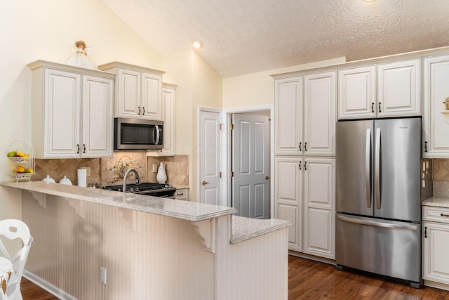 6681 Lakeview Cir, Canal Winchester, OH 43110 - kitchen featuring appliances with stainless steel finishes, a breakfast bar area, a peninsula, light stone counters, and lofted ceiling