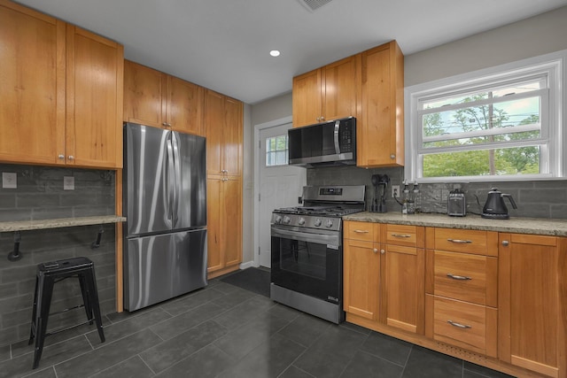 198 Loveman Ave, Worthington, OH 43085 - kitchen featuring appliances with stainless steel finishes, tasteful backsplash, light stone countertops, and dark tile patterned flooring