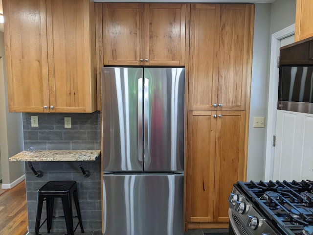 198 Loveman Ave, Worthington, OH 43085 - kitchen featuring appliances with stainless steel finishes, baseboards, wood finished floors, brown cabinetry, and light stone countertops