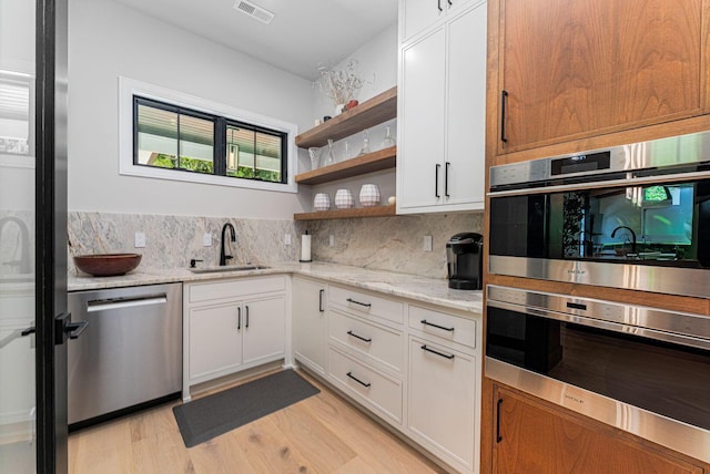 8159 Riverside Dr, Powell, OH 43065 - kitchen with stainless steel appliances, a sink, open shelves, tasteful backsplash, and light wood-style flooring