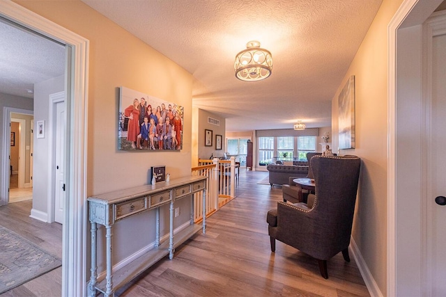 10641 Arrowwood Dr, Plain City, OH 43064 - hallway featuring wood finished floors, an upstairs landing, a textured ceiling, a chandelier, and baseboards