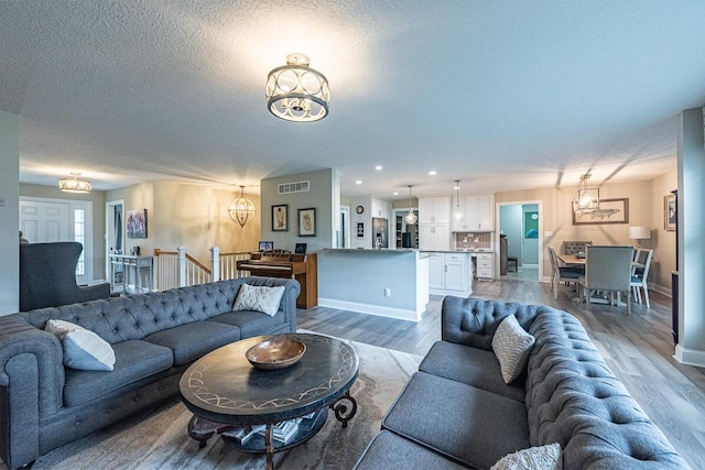 10641 Arrowwood Dr, Plain City, OH 43064 - living area with a chandelier, wood finished floors, baseboards, a textured ceiling, and recessed lighting
