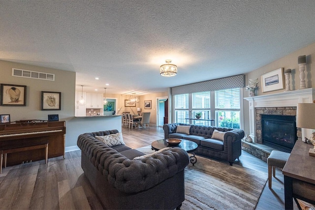 10641 Arrowwood Dr, Plain City, OH 43064 - living room with a chandelier, wood finished floors, a fireplace, a textured ceiling, and recessed lighting