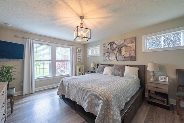 10641 Arrowwood Dr, Plain City, OH 43064 - bedroom featuring wood finished floors, a chandelier, baseboards, and a textured ceiling
