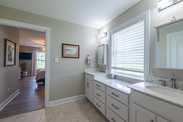 10641 Arrowwood Dr, Plain City, OH 43064 - full bath featuring double vanity, connected bathroom, tile patterned flooring, a textured ceiling, and baseboards