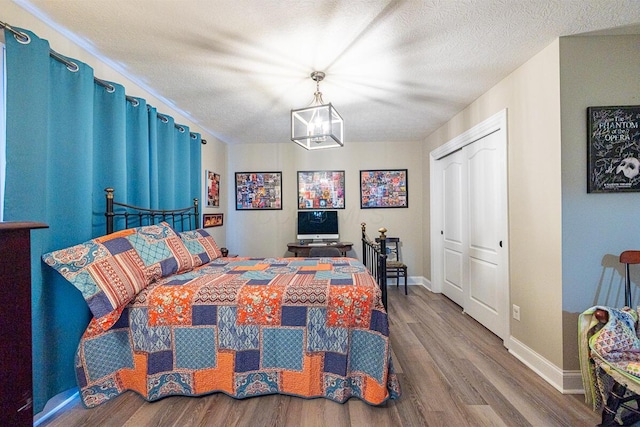 10641 Arrowwood Dr, Plain City, OH 43064 - bedroom with wood finished floors, a chandelier, baseboards, a closet, and a textured ceiling