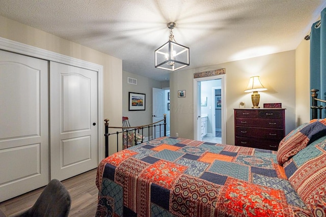 10641 Arrowwood Dr, Plain City, OH 43064 - bedroom with wood finished floors, a chandelier, a closet, and a textured ceiling