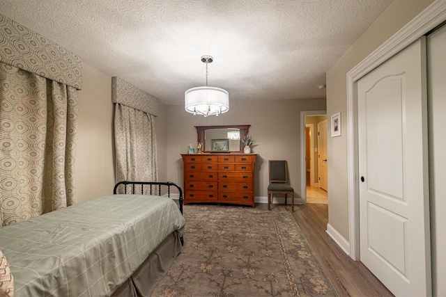 10641 Arrowwood Dr, Plain City, OH 43064 - bedroom with wood finished floors, a chandelier, a textured ceiling, and baseboards