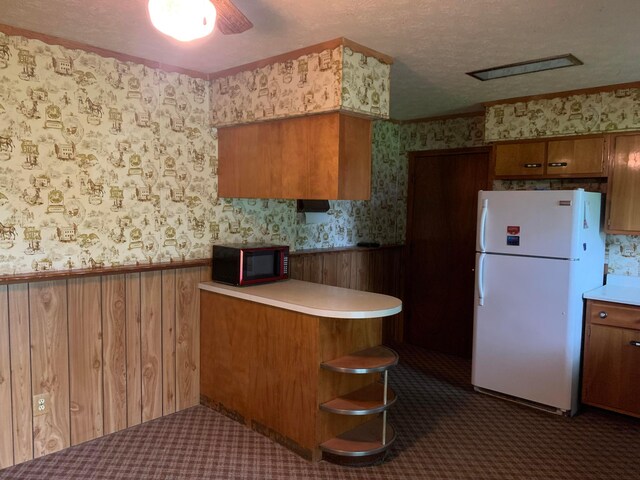 101 Gale Ct, Circleville, OH 43113 - kitchen with black microwave, freestanding refrigerator, wallpapered walls, wainscoting, and brown cabinets