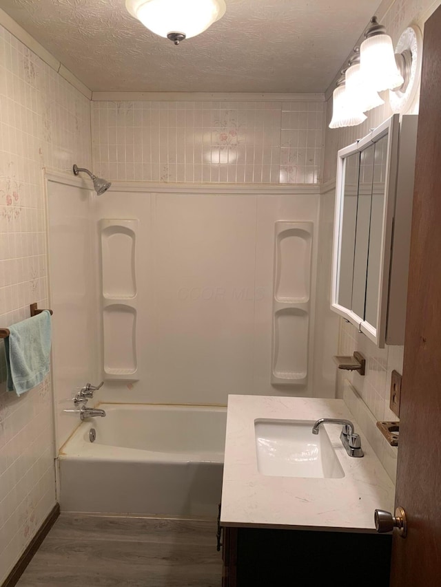 101 Gale Ct, Circleville, OH 43113 - bathroom with wood finished floors, shower / bath combination, tile walls, vanity, and a textured ceiling
